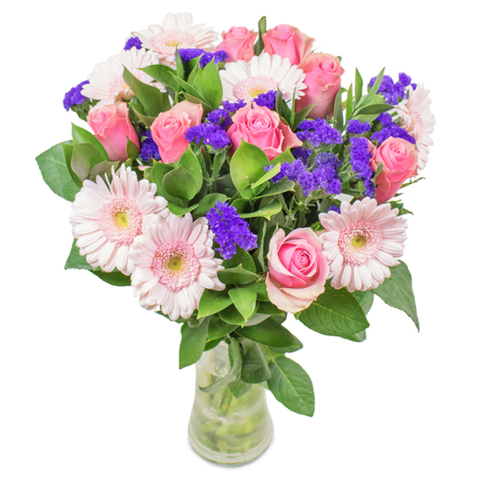 Crafted by a South Croydon florist, this vibrant floral arrangement is presented in a clear glass vase set against a crisp white background, embodying a harmonious blend of approximately seven to nine pink roses-some in tight buds, others beginning to reveal their elegant spiral centers. Intertwined with five to seven pale pink gerbera daisies, their wide, rounded petals and creamy centers contrast beautifully with vivid purple statice or limonium, which introduces striking texture and a pop of contrast reminiscent of the lively palette seen in South Croydon's flower stalls near the station. The deep green foliage below creates a dense, abundant base, echoing the greenery at Purley Way Playing Fields. The transparent vase reveals the natural stems and fresh water, emphasizing freshness and readiness for prompt local delivery. Whether presented for a birthday on Addiscombe Road, an anniversary, or as a delightfully fresh piece for an office along Brighton Road, this arrangement of roses, gerberas, and purple accent blossoms exudes celebration, affection, and the thoughtful artistry at the heart of South Croydon Florist.